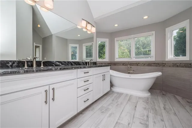 a spacious bathroom with a double vanity sink a large mirror and a bathtub