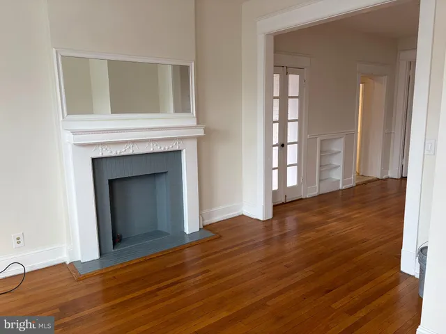 an empty room with wooden floor and a fireplace
