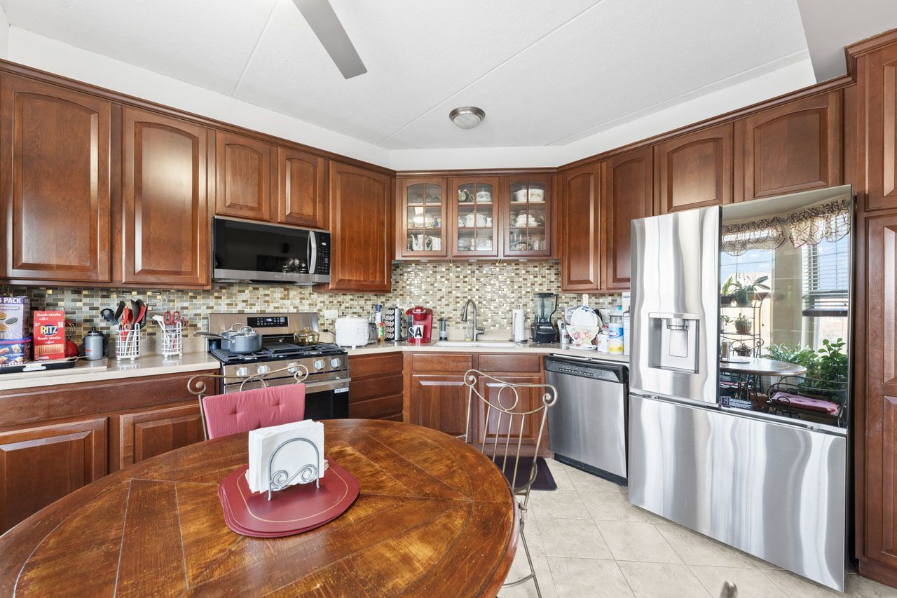 511 Prestwick Lane, Unit 302 Wheeling, IL 60090 - Photo 9 of 24 a kitchen with stainless steel appliances granite countertop a stove a refrigerator a sink dishwasher a dining table and chairs with wooden floor