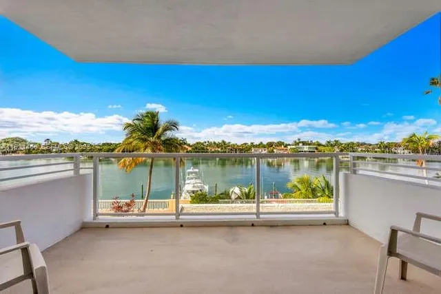 a large white kitchen with granite countertop lots of white cabinets appliances and furniture