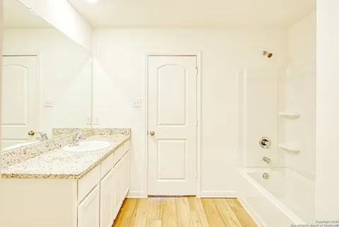 a bathroom with a granite countertop sink and a bathtub