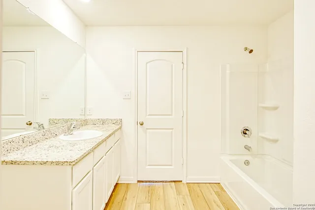 a bathroom with a granite countertop sink and a bathtub
