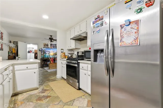 a kitchen with stainless steel appliances a refrigerator sink and white cabinets