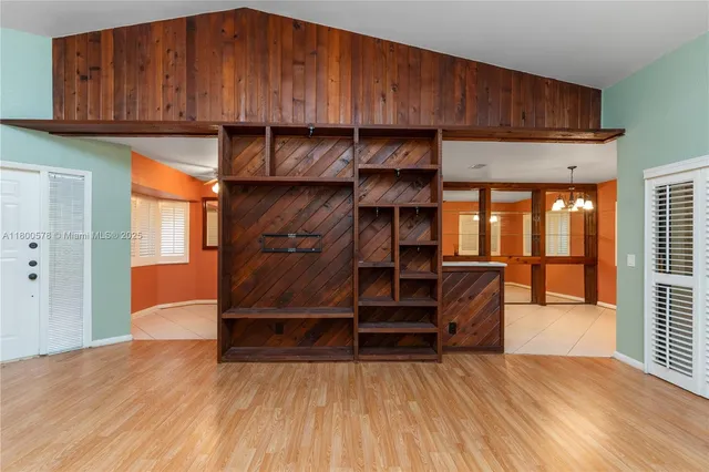 an empty room with wooden floor closet and windows