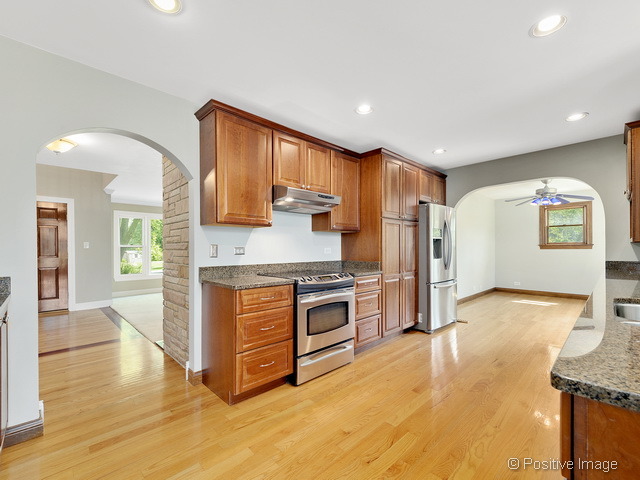 908 Ranch Road Wheaton, IL 60187 - Photo 6 of 25 a kitchen with stainless steel appliances granite countertop a stove a sink and a refrigerator with wooden floor