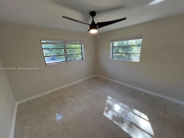 en empty room with windows and ceiling fan