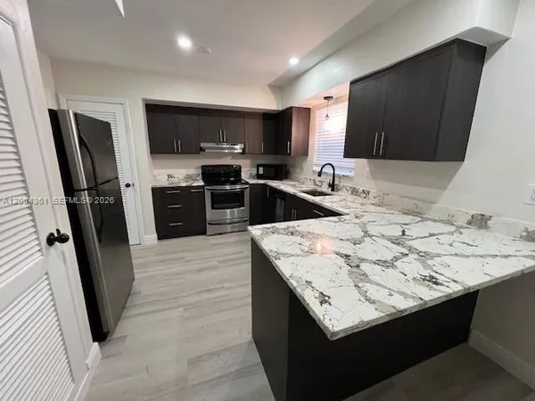 a kitchen with stainless steel appliances kitchen island granite countertop a sink stove and refrigerator