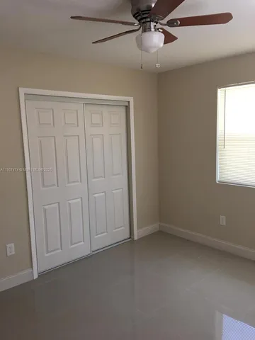 an empty room with windows and fan