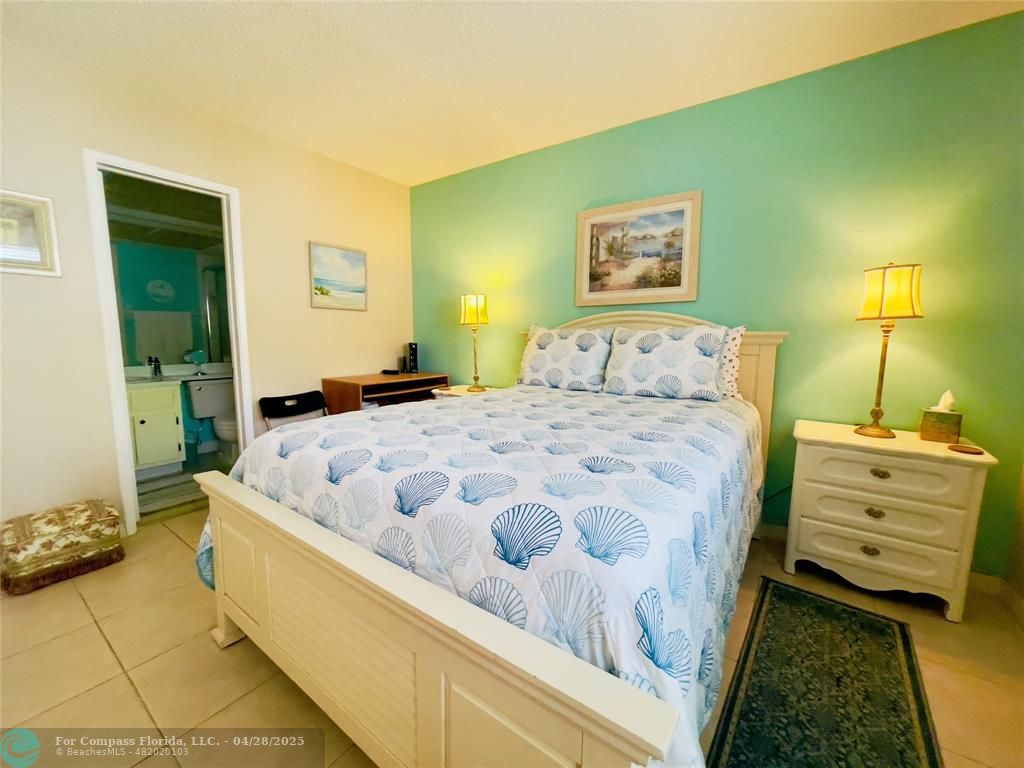 651 Pine Drive, Unit 207 Pompano Beach, FL 33060 - Photo 12 of 18 a bedroom with a bed and a lamp with the mirror