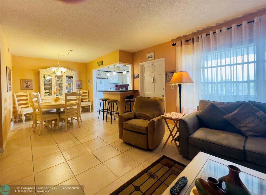 651 Pine Drive, Unit 207 Pompano Beach, FL 33060 - Photo 9 of 18 a living room with furniture a dining table and a chandelier