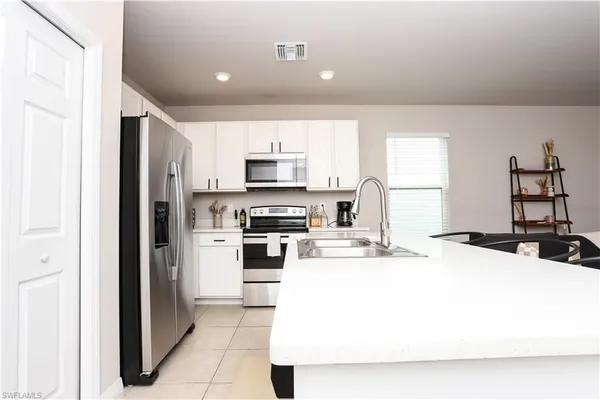 a kitchen with kitchen island a sink a stove a refrigerator and white cabinets