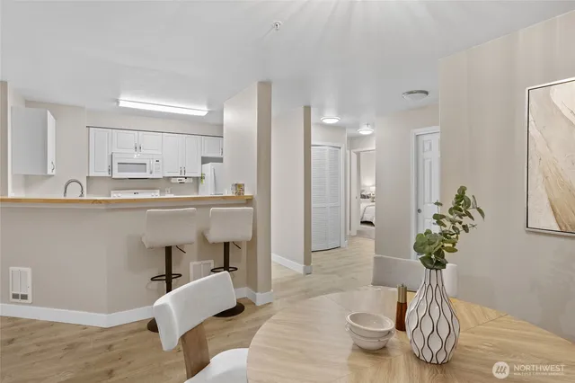a dining room with wooden floor a chandelier a glass table and chairs