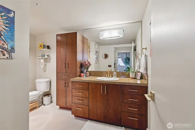 a bathroom with a granite countertop sink mirror and toilet