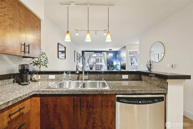 a kitchen with stainless steel appliances granite countertop a sink a stove and a wooden cabinets