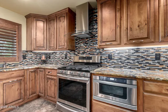 a kitchen with granite countertop a stove top oven cabinetry a sink and dishwasher a oven with wooden cabinets