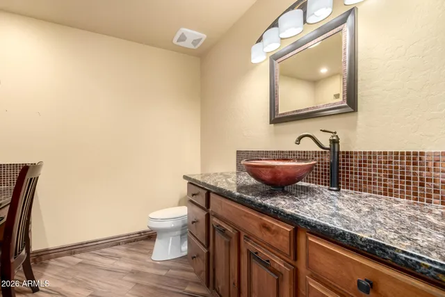 a bathroom with a granite countertop toilet sink and mirror