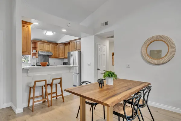 a kitchen with stainless steel appliances granite countertop a dining table chairs and a refrigerator