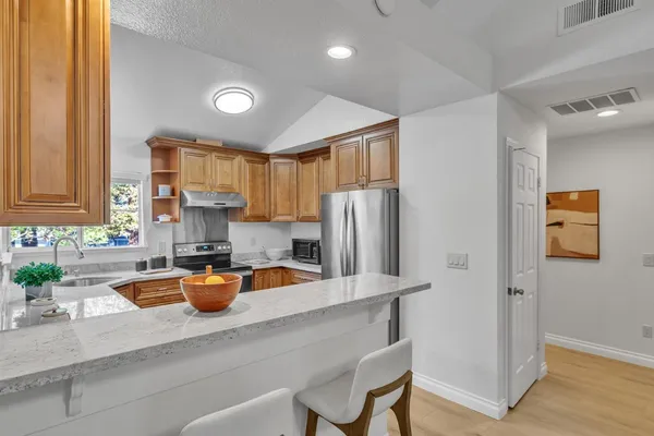 a kitchen with stainless steel appliances granite countertop a refrigerator a sink a stove and white cabinets