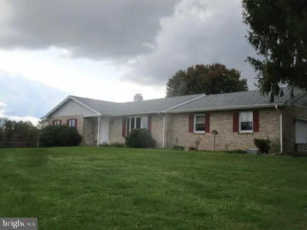 a front view of a house with a yard and trees