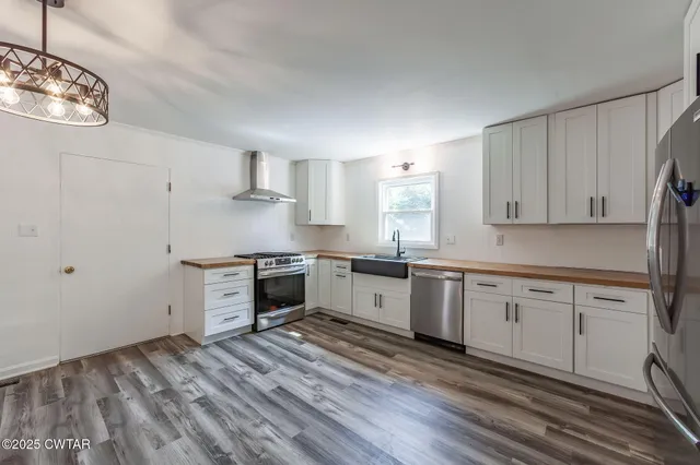 a kitchen with granite countertop a stove a sink and a refrigerator