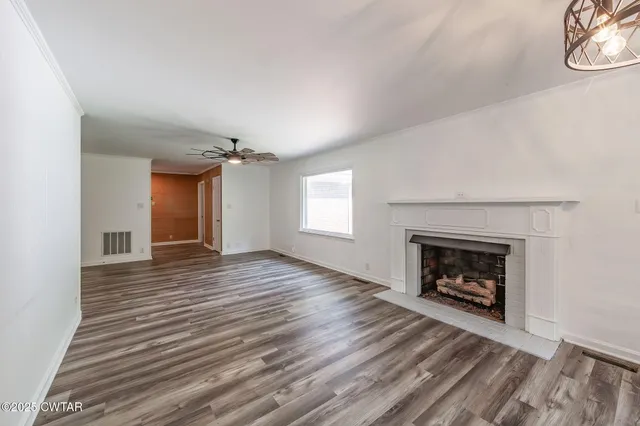 a view of an empty room with a fireplace and window