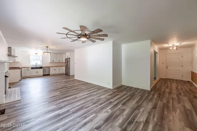 a view of kitchen and empty room with wooden floor