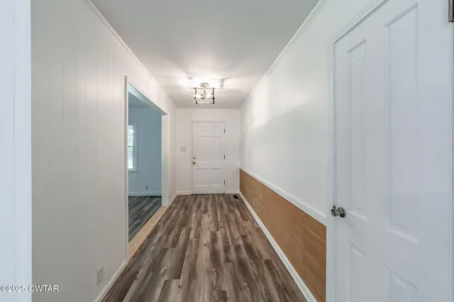 a view of a hallway with wooden floor and a chandelier