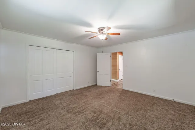 an empty room with chandelier fan and windows
