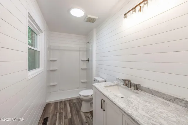a bathroom with a granite countertop sink toilet and shower
