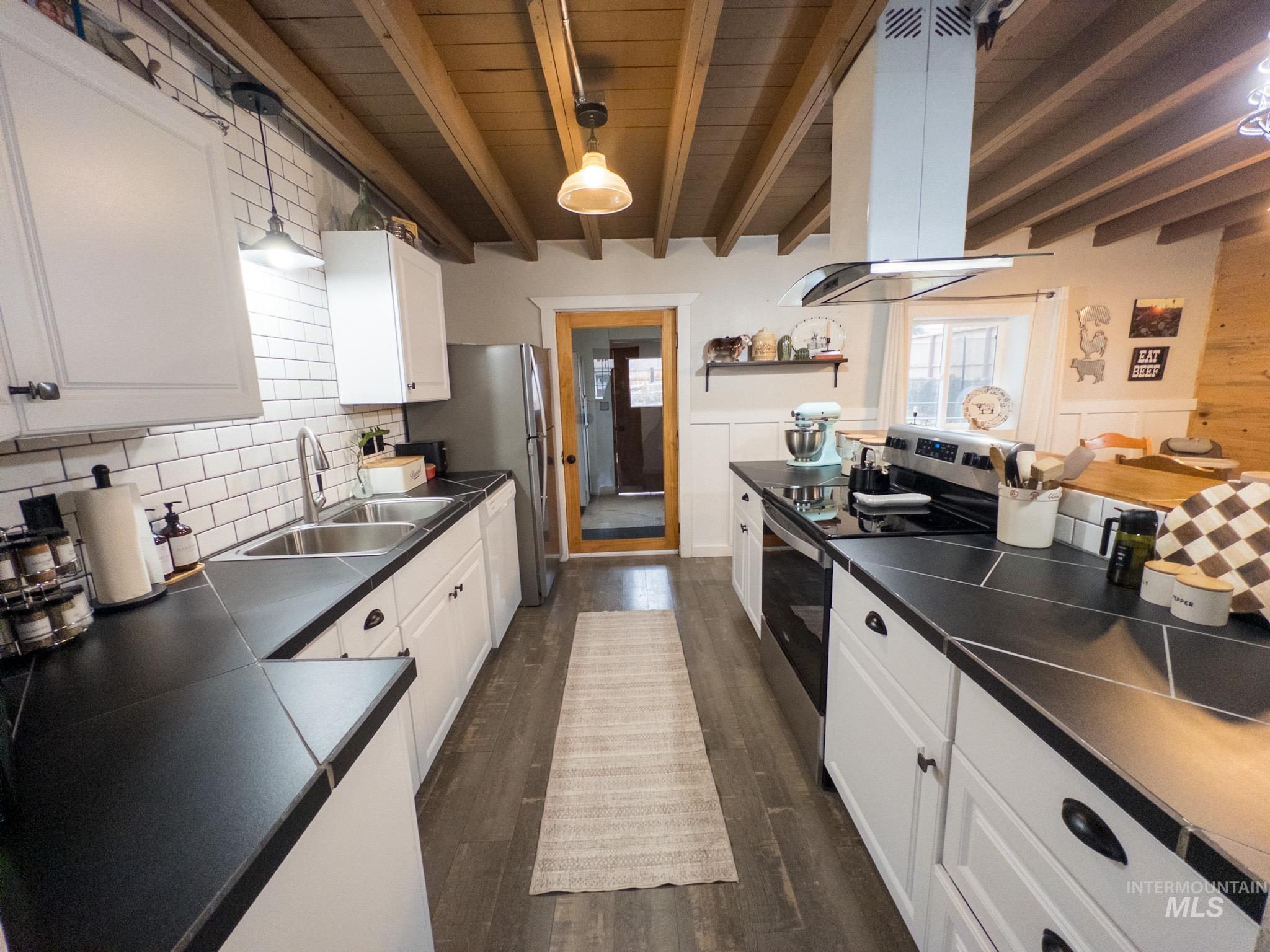 55 South Superior Street Cambridge, ID 83610 - Photo 8 of 31 Kitchen featuring dark countertops, white cabinetry, stainless steel appliances, island exhaust hood, and decorative light fixtures