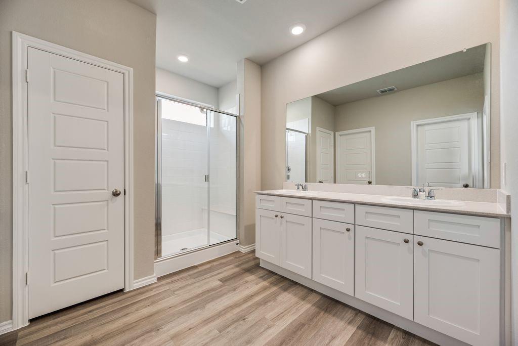 752 Rubicon Road Justin, TX 76247 - Photo 17 of 19 Contemporary bathroom featuring a dual vanity with white shaker-style cabinetry, a spacious mirrored wall, and a walk-in shower with clear glass enclosure