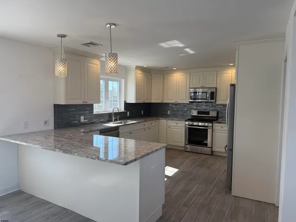 a kitchen with stainless steel appliances granite countertop a stove a sink and a microwave