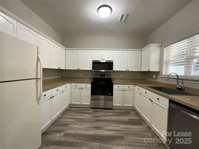 a view of an empty room with wooden floor and window