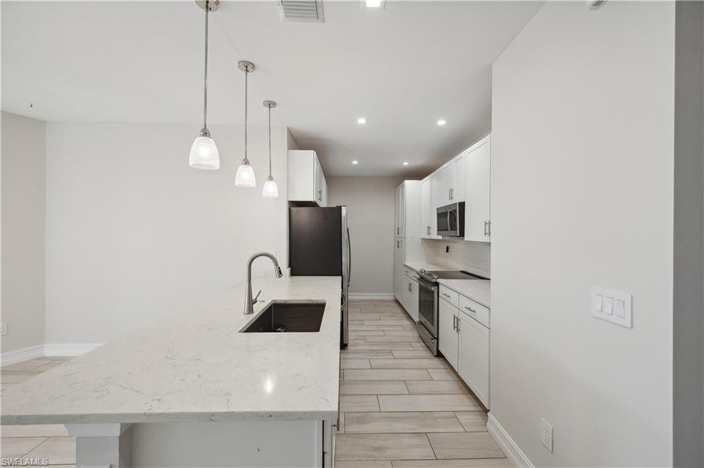 7640 Morgan Way Naples, FL 34119 - Photo 7 of 12 a kitchen with stainless steel appliances granite countertop a sink a stove and a refrigerator