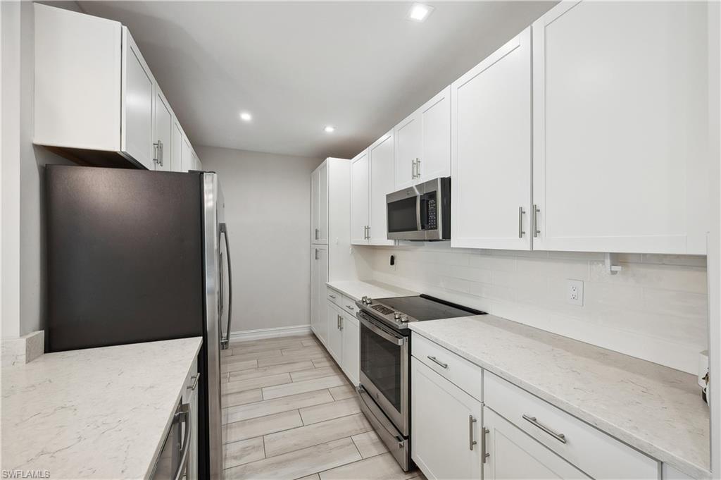 7640 Morgan Way Naples, FL 34119 - Photo 8 of 12 a kitchen with stainless steel appliances kitchen island granite countertop a refrigerator a stove and a sink