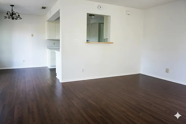 a view of an empty room with wooden floor and a sink