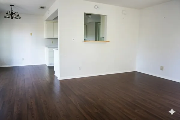 a view of an empty room with wooden floor and a sink