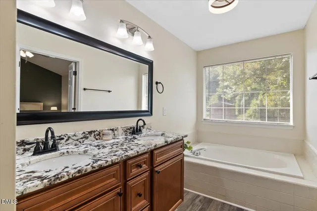a bathroom with a granite countertop tub a sink and a large mirror