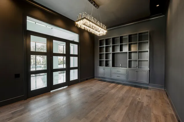 an empty room with wooden floor a ceiling fan a fireplace and windows