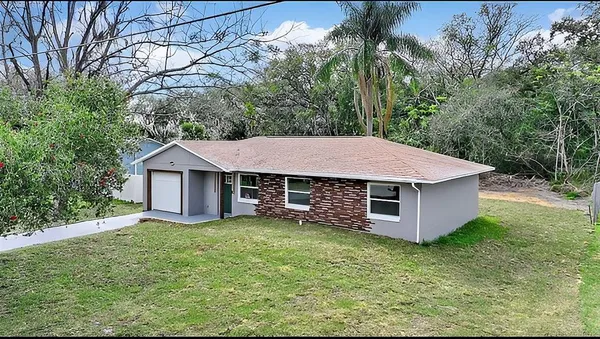 a view of a house with a yard and large tree
