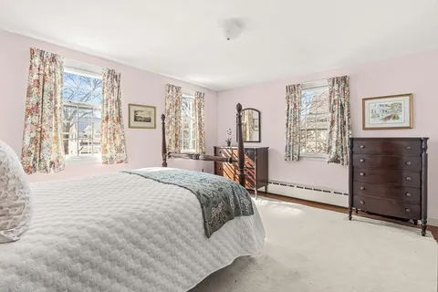 a spacious bedroom with a bed a dresser and next to a window