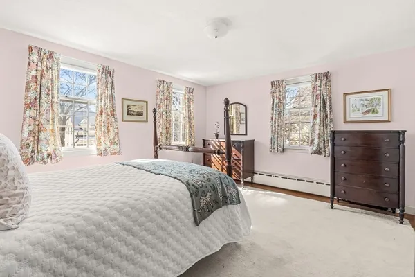 a spacious bedroom with a bed a dresser and next to a window
