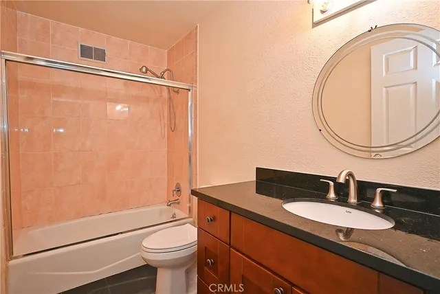 a bathroom with a granite countertop toilet sink and mirror