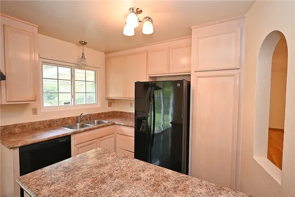 a kitchen with stainless steel appliances granite countertop a refrigerator a sink dishwasher a stove and white cabinets with wooden floor