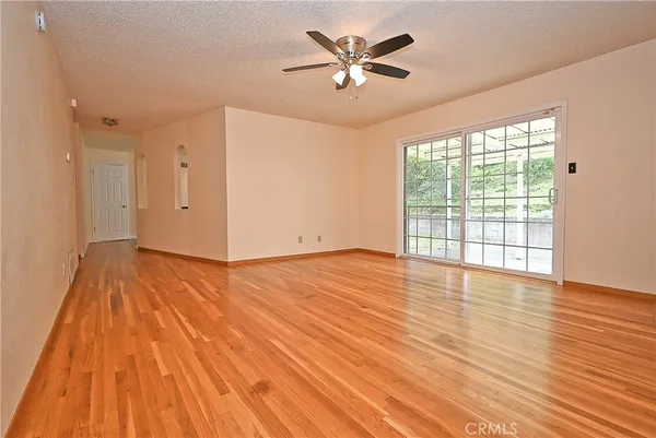 a view of empty room with wooden floor and fan