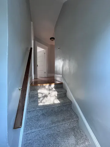a view of a hallway to a livingroom with wooden floor and a rug