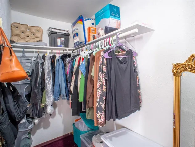 a view of walk in closet with clothes and shoes