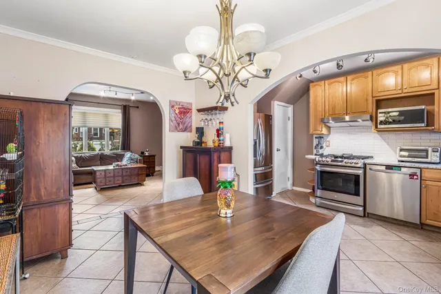 a living room with stainless steel appliances furniture a chandelier and a kitchen view
