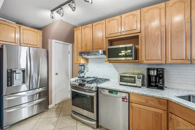 a kitchen with granite countertop cabinets stainless steel appliances and a window