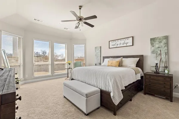 a spacious bedroom with a bed a couch and large window